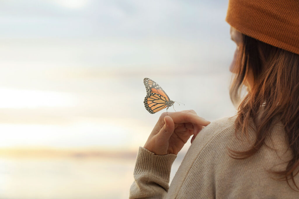 Colorful butterfly is laying on a woman's hand